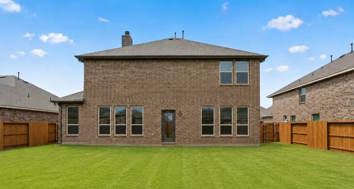 Two-story brick Houston home with an open green backyard lawn after removing the patio cover, garden bed, and stepping-stone pathway.