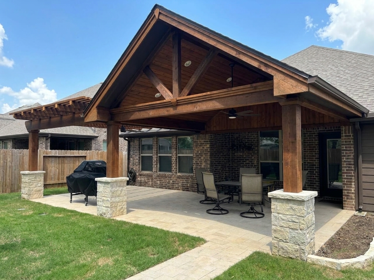 Custom gable patio cover with cedar beams, exposed truss details, masonry column bases, and an attached open-air pergola extension in a Houston backyard.